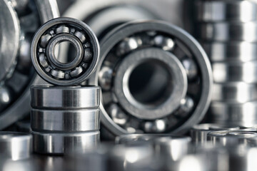 Radial ball bearings close-up in silver color for mechanical engineering, machine tools and equipment. Round steel bearings of various sizes with balls at the base with a blurred background.