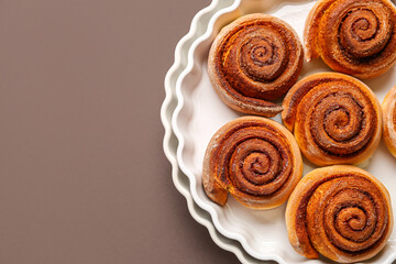 Baking dishes with tasty cinnamon rolls on brown background