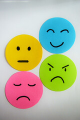 Different moods on yellow, blue, pink and green paper faces. Concept of emotions on white background.