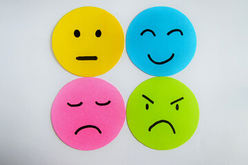Different moods on yellow, blue, pink and green paper faces. Concept of emotions on white background.