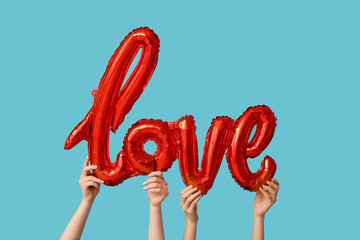 Women with air balloon in shape of word LOVE on blue background. Valentine's Day celebration