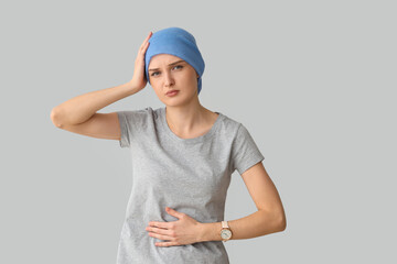 Young woman after chemotherapy suffering from pain on light background. Stomach cancer concept