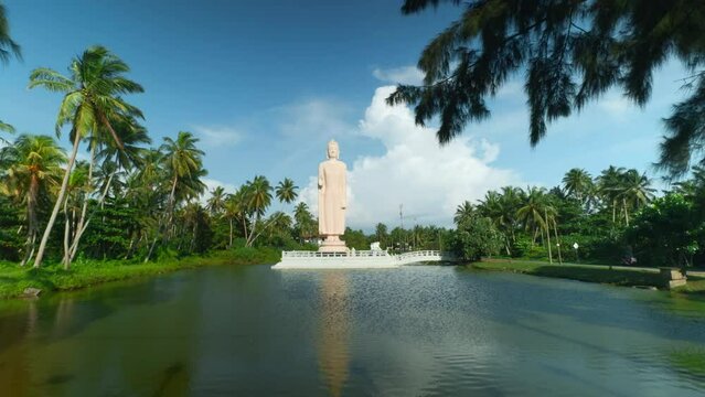 Tsunami Honganji Vihara, Hikkaduwa, Sri Lanka. Action. Beautiful white statue among green palm trees and blue cloudy sky.
