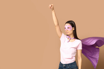 Young woman in superhero costume on beige background. Women's history month