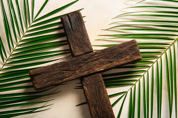 Wooden cross with palm leaves on white background