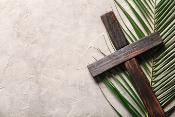 Wooden cross and palm leaf on grey background
