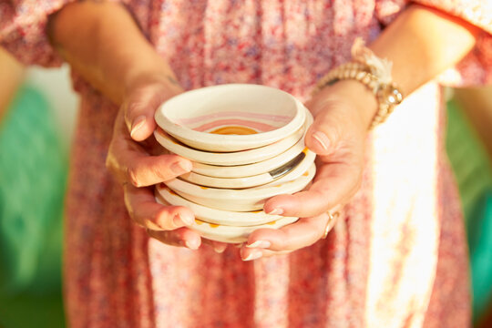 Woman's hands holding a stack of handmade plates.