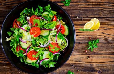 Salad from tomatoes, cucumber, red onions and lettuce leaves. healthy summer vitamin menu. vegan vegetable food. vegetarian dinner table. top view. flat lay
