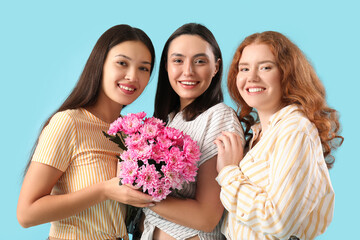 Beautiful young women with bouquet of pink chrysanthemum flowers on blue background. International Women's Day