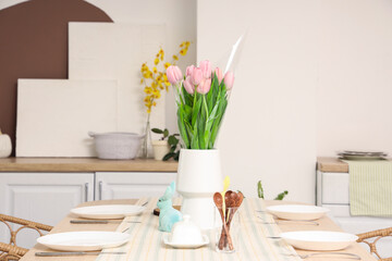 Vase with tulips and Easter rabbit on dining table in kitchen