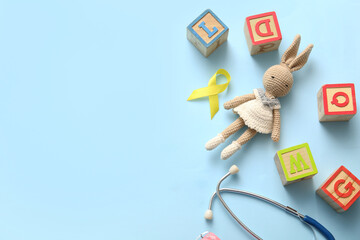 Golden ribbon with stethoscope and toys on blue background. Children cancer awareness concept