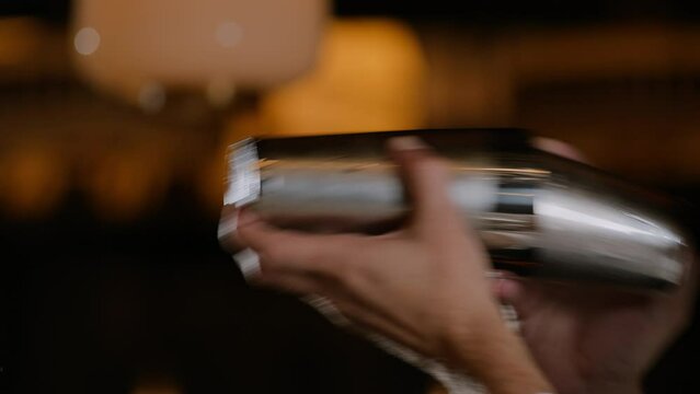 Closeup shot of a bartender shaking a cocktail in a cocktail shaker
