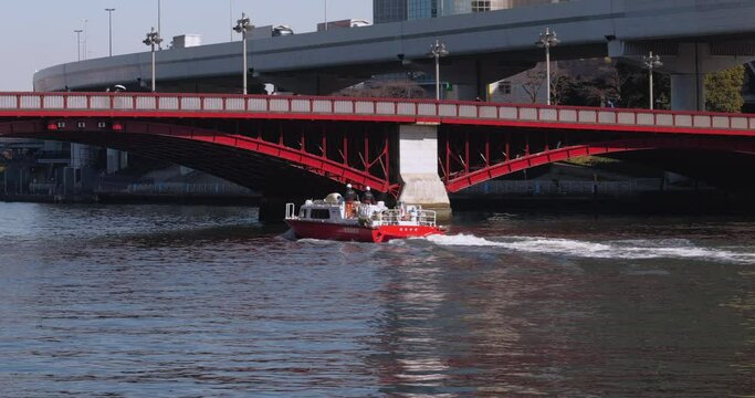 赤い橋の下を通過する赤い消防艇。