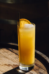 orange juice drink with orange slice and drinking straw on whiskey barrel