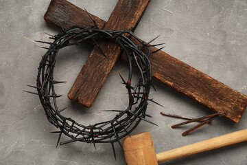 Crown of thorns with wooden cross, hammer and nails on grey grunge background