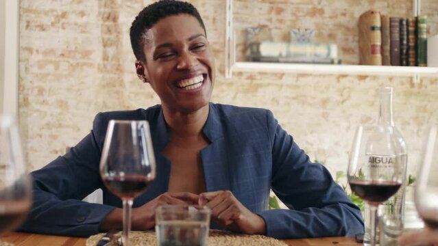 Happy black entrepreneur laughing at joke and clapping hands during business lunch in restaurant