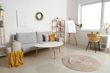Interior of living room with Easter wreath, easel and sofa