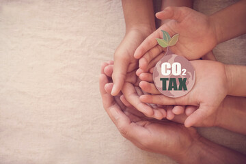 Hands holding CO2 tax on earth paper cut, carbon tax, net zero concept