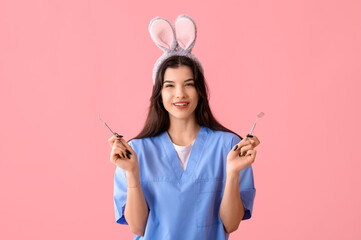 Female dentist in bunny ears with tools on pink background. Easter celebration