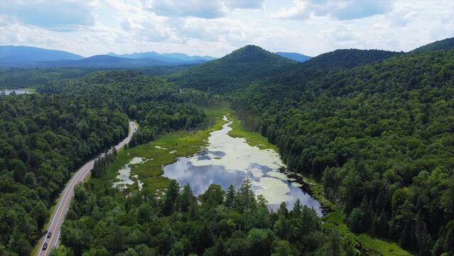 Aerial Footage of Highway Cutting Through the Mountains of Upstate New York next to a Reflective Lake