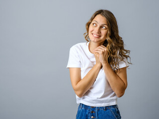 Portrait of a casual pretty young smiling woman thinking about something isolated