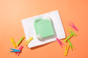 A turquoise bottle of laundry detergent is placed on a folded white cloth, surrounded by colorful...