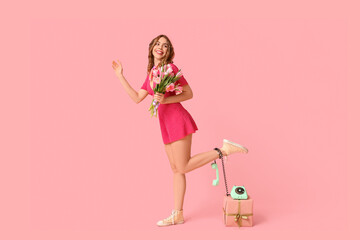 Young woman with retro telephone, gift box and bouquet of beautiful tulips on pink background....