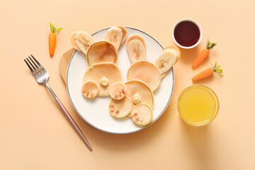 Funny Easter bunny pancakes with glass of orange juice on yellow background