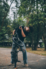 Young handsome bearded man taking a break while travelling the city with his bicycle using his digital tablet looking away thoughtfully