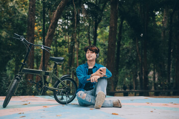 Young handsome bearded man taking a break while travelling the city with his bicycle using his digital tablet looking away thoughtfully