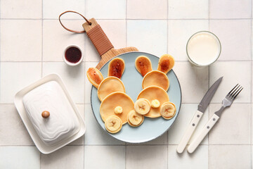 Funny Easter bunny pancakes with glass of milk on white tile background