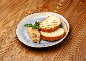 Duck meat pate with bread in a plate on a wooden background