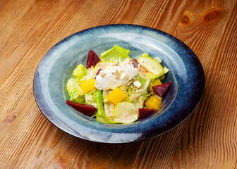 Beetroot and cottage cheese salad, with lettuce leaves in a plate on a wooden background
