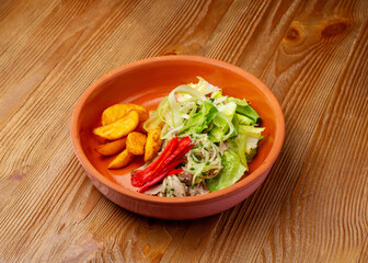 Salad with duck, potatoes and lettuce in a plate on a wooden background