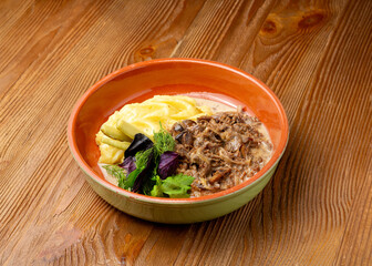 Beef stroganoff with mashed potatoes in a plate on a wooden background