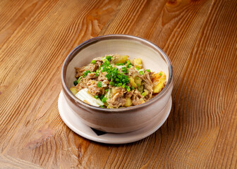 Pulled beef meat with potatoes in a plate on a wooden background