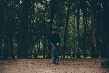 Young handsome bearded man taking a break while travelling the city with his bicycle using his digital tablet looking away thoughtfully