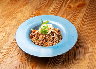 Duck meat with buckwheat in a plate on a wooden background