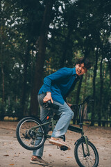 Fototapeta premium Young handsome bearded man taking a break while travelling the city with his bicycle using his digital tablet looking away thoughtfully