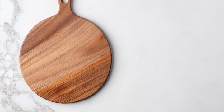 Top view of a round wooden serving board with handle on a marble table. Kitchenware, template with copy space. Flat lay design, mockup. Cooking concept.