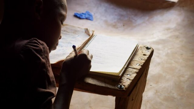 black african children kid study alone writing on notebook preparing homework for school in remote village of Africa