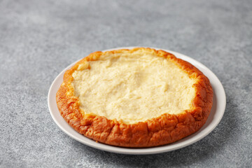 Curd casserole piece in a plate with berries on the table.