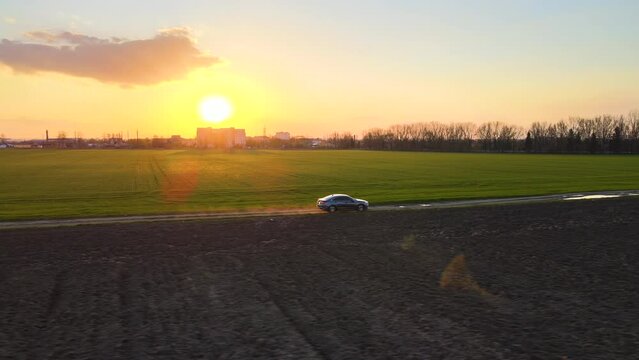Aerial view of Subaru Legacy sedan car driving fast on dirt road at sunset. Traveling by vehicle concept