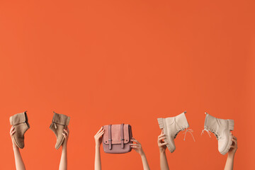 Women with stylish boots and bag on orange background