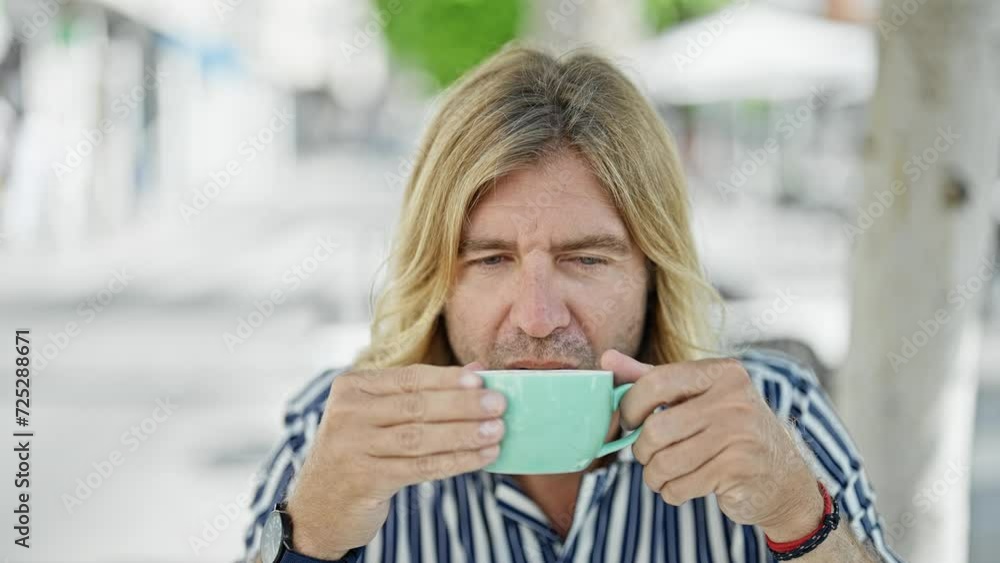 Sticker blond man enjoys coffee on city street terrace, showcasing urban lifestyle and relaxation.