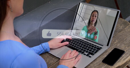 Image of speech bubble with thumbs up and numbers growing over woman using laptop on image call