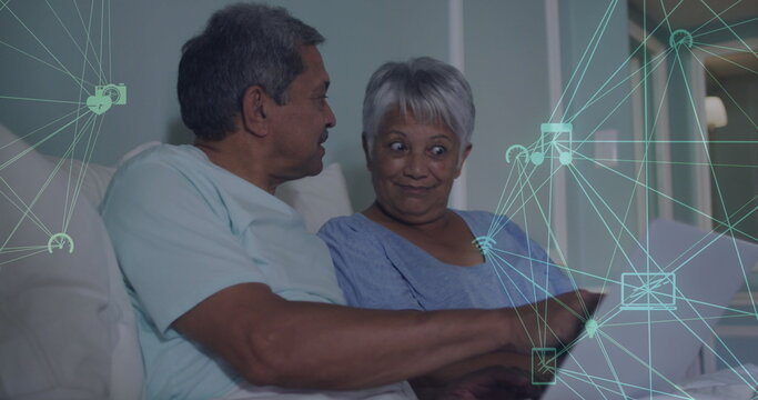 Image of networks of connections spinning over senior couple using laptop at home