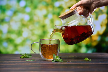 natural organic herbal tea pours in a glass from glass teapot
