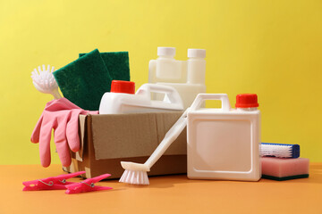 Front view of set of different detergents displayed on a yellow background. White plastic canisters...
