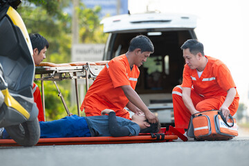 The paramedic  is assisting an injured man in an emergency situation on the road. - Powered by Adobe